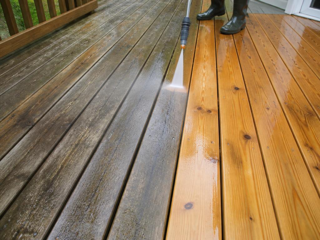 Wooden deck being washed, weathered gray boards next to restored warm wood